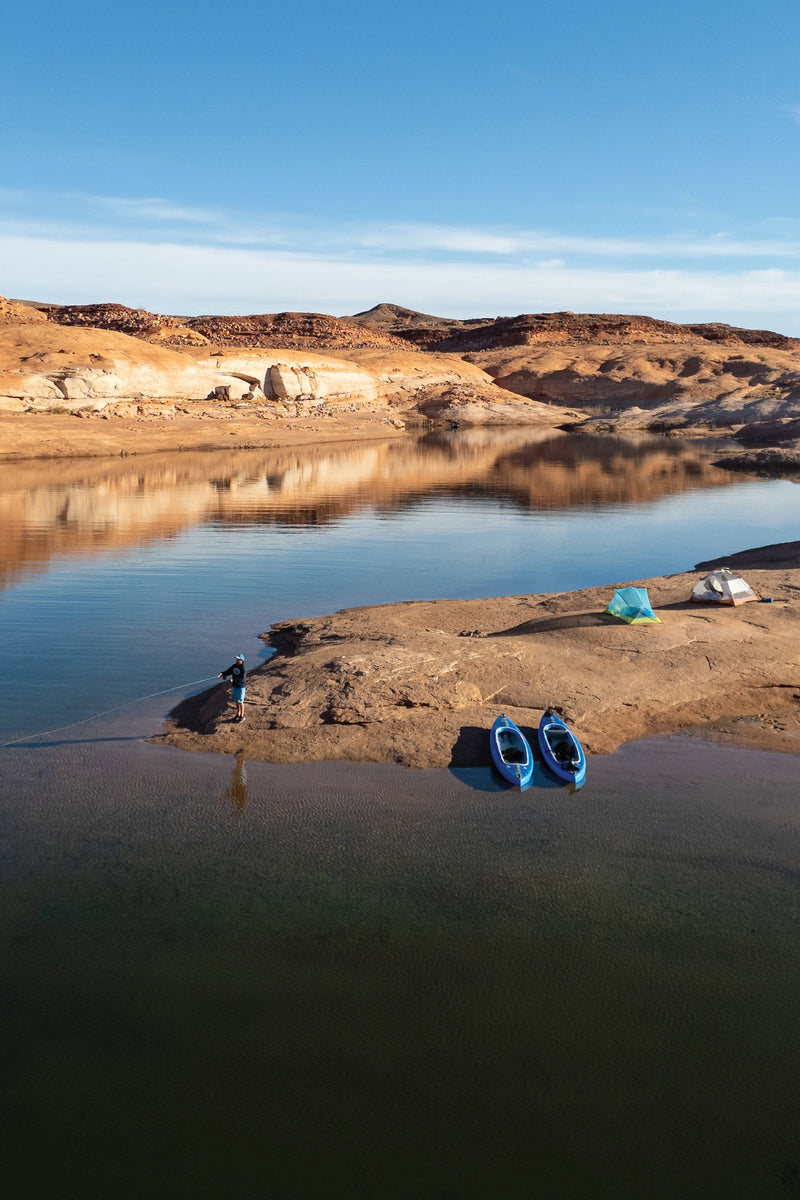 An aerial drone view of two blue Advanced Elements AirVolution Series inflatable kayaks resting on a sandy peninsula of a desert river.