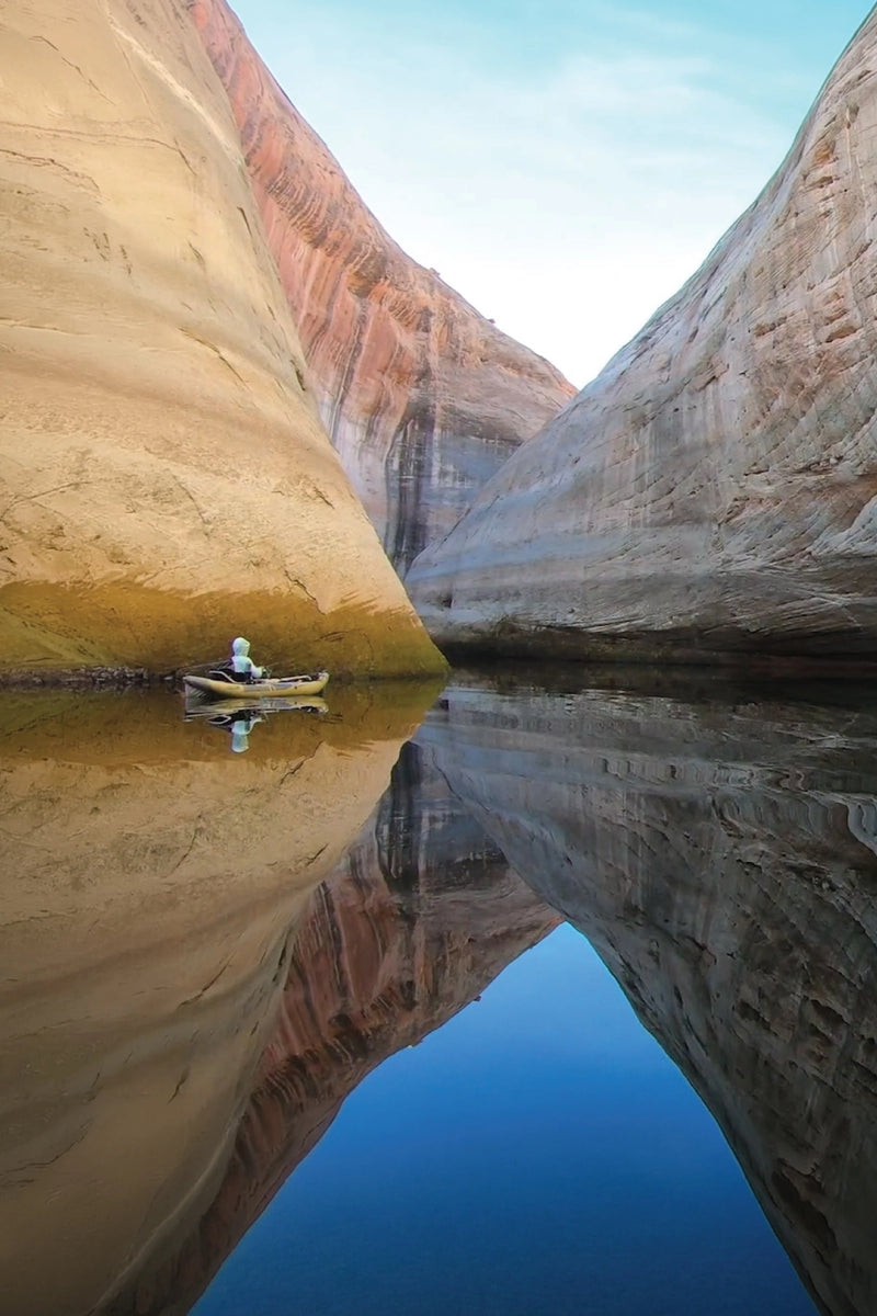 A person paddling an Advanced Elements StraitEdge Series inflatable kayak down a calm river.