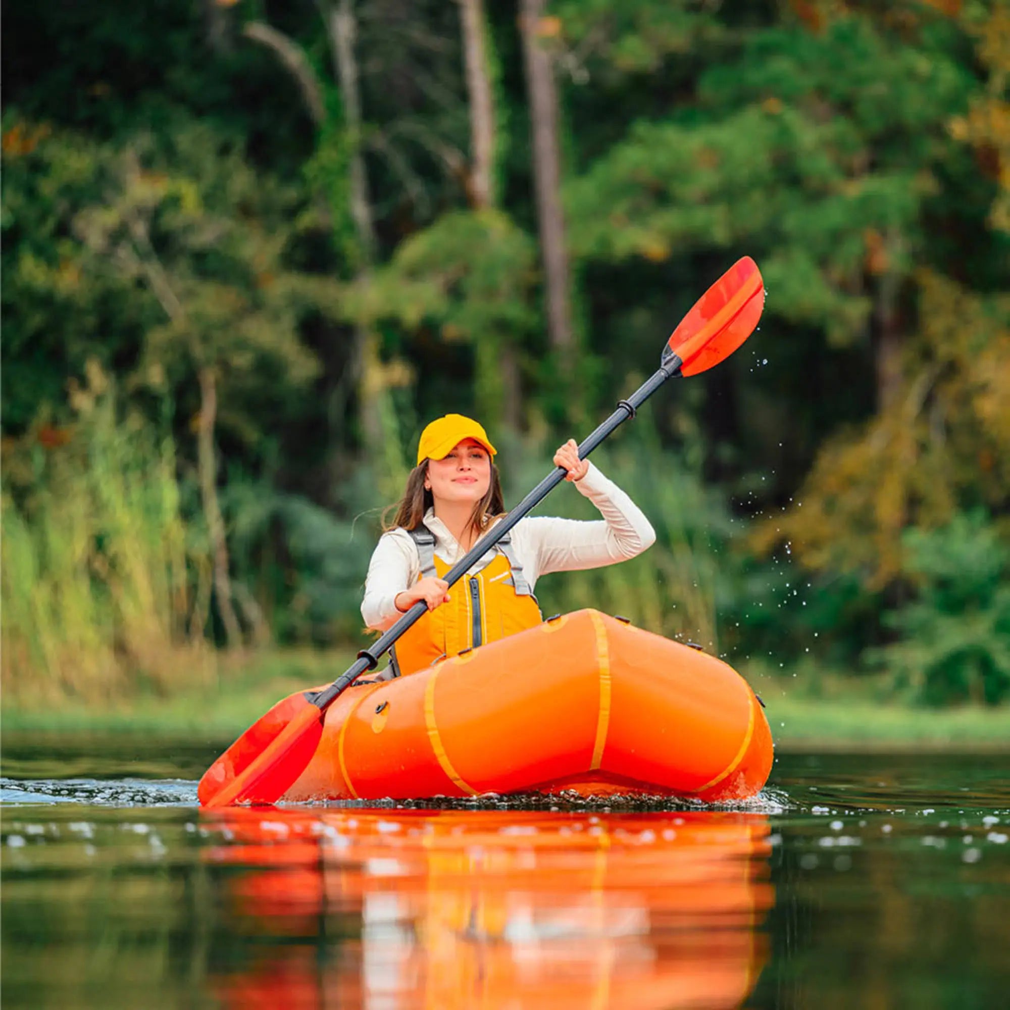 Woman on an orange Advanced Elements packrafting boat exploring calm water outdoors