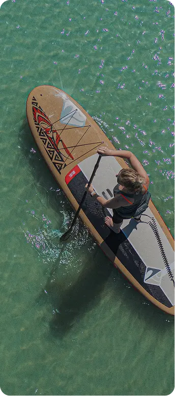 Woman paddle boarding on clear blue water during a scenic outdoor adventure
