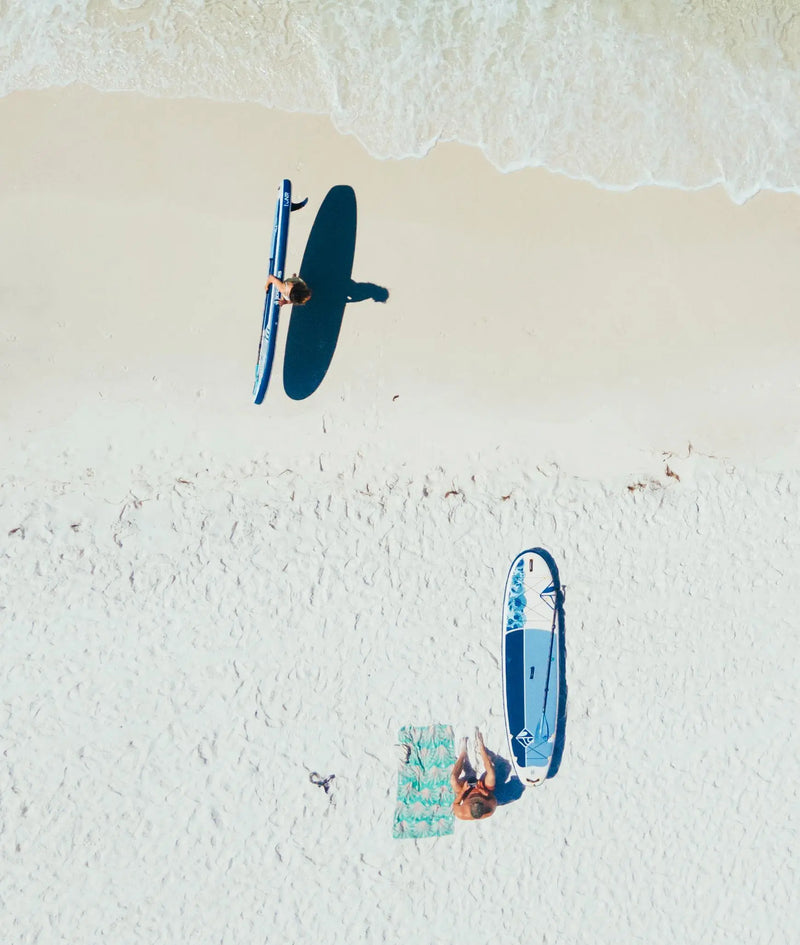Aerial view of two people on the beach with Boardworks paddle boards by the shoreline