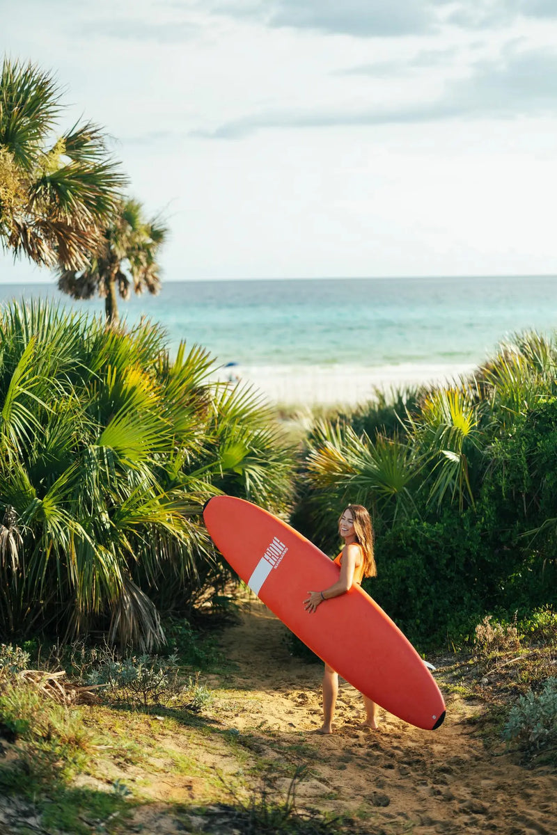 Woman holding a Boardworks surfboard in front of the ocean at the beach